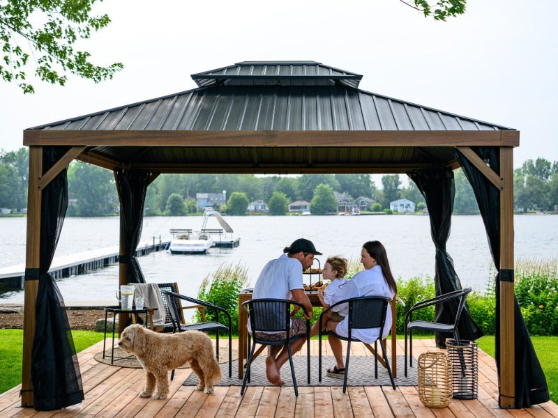 Gazebo Penguin Yosemite Gazebo Aluminum Frame Wood Finish 10'x12' front view of gazebo with family sitting under in front of a lake