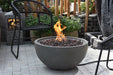 Backyard Lifestyles Modeno Nantucket 26"/40,000 BTU Grey Concrete Natural Gas Firebowl front view of fire bowl with flame outdoors with patio furniture