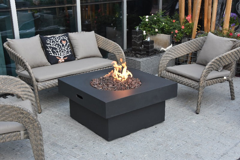 Backyard Lifestyles Modeno - Branford Fire Table in Black front angle view of fire table with lava rocks and flame on a deck with patio furniture