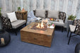 Backyard Lifestyles Modeno - Wilton Fire Table in Redwood front angle view of fire table on deck with flame surrounded by patio furniture