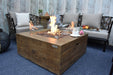 Backyard Lifestyles Modeno - Wilton Fire Table in Redwood front close angle view of fire table with flame and flame guard on a deck with patio furntiure