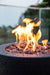 Backyard Lifestyles Modeno Lava Tube Concrete Propane Fire Pit in Black close up view of lava rocks and flame